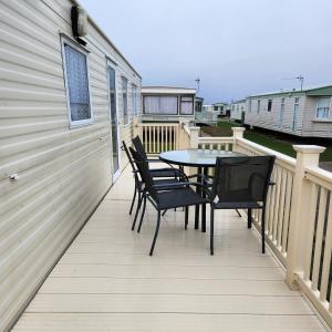 a patio with a table and chairs on a deck at 3 BEDROOM CARAVAN AT THE GRANGE HOLIDAY PARK, CHAPEL ROAD INGOLDMELLS in Addlethorpe