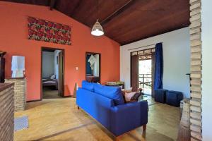 uma sala de estar com um sofá azul e uma parede laranja em Casa Vilacentro - Imbassaí em Imbassaí
