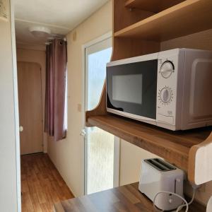 a microwave sitting on a shelf in a kitchen at 3 BEDROOM CARAVAN AT THE GRANGE HOLIDAY PARK, CHAPEL ROAD INGOLDMELLS in Addlethorpe