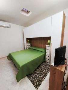 a bedroom with a green bed and a television at Casa vacanze Galena in Iglesias