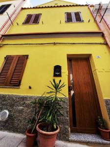 a yellow building with a door and some plants at Casa vacanze Galena in Iglesias