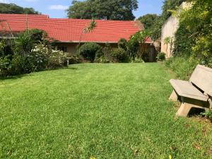 a yard with a bench in the grass at Coz Guesthouse in Randburg in Johannesburg