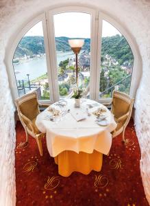 a dining room table with a large window at Hotel Schloss Rheinfels in Sankt Goar