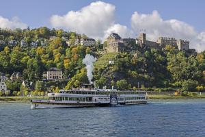 a cruise ship on the water in front of a castle at Hotel Schloss Rheinfels in Sankt Goar