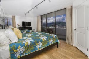 a bedroom with a bed with a blue and white comforter at Hawaiian Hospitality in Honolulu