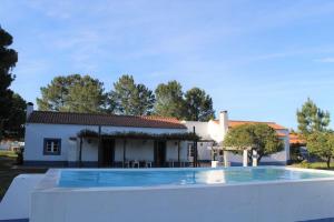 a villa with a swimming pool in front of a house at Casa do Pinheiro in Alcácer do Sal