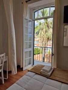 a bedroom with a bed and a large window at Hospedaria Pôr do Sol in Funchal