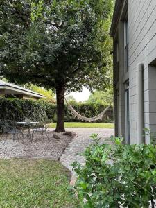 Un árbol con una mesa y sillas al lado de un edificio. en Fisherton Alquiler Temporario, en Rosario