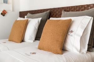 a bed with white and brown pillows on it at Rua de Tr&aacute;s Apartments in Porto