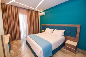 1 dormitorio con 1 cama grande y pared azul en Hotel Vivas en Durrës