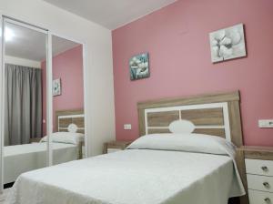 Habitación de color rosa con 2 camas y espejo. en HOTEL NUEVO ESPARTINAS en Espartinas
