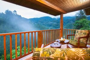 eine Veranda mit einem Tisch und Stühlen auf dem Balkon in der Unterkunft Gorilla Leisure Lodge in Kisoro