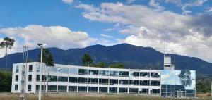 San AlbertoにあるHOTEL COLOMBIA BYBの山を背景にしたガラス窓のある建物