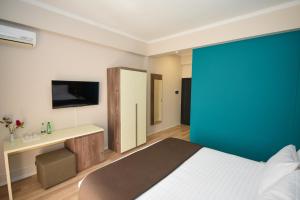 een slaapkamer met een bed en een blauwe muur bij Hotel Vivas in Durrës