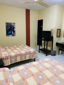 una habitación de hotel con 2 camas y un piano en Hotel Del Valle en El Naranjo