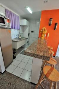 a kitchen with a counter and a refrigerator and chairs at Apartamento na Praia de Iracema, Meireles. in Fortaleza