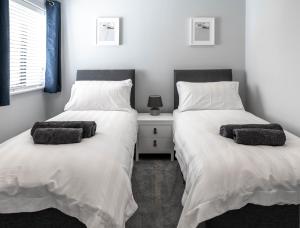 twee bedden naast elkaar in een slaapkamer bij Modern new build, Close to the beach and town in Bude