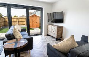 a living room with two couches and a television at Modern new build, Close to the beach and town in Bude
