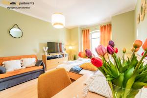 - un salon avec un canapé et une table avec des tulipes dans l'établissement Baltic Apartments - Regina Maris, à Świnoujście
