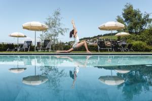 a woman is sitting on the edge of a swimming pool at Wellnesshotel Erica in Nova Ponente