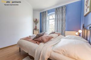 a bedroom with blue walls and a bed with pillows at Baltic Apartments - Regina Maris in Świnoujście