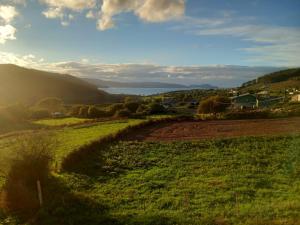 a field of grass with the sun shining on it at Hostal Restaurante Os Faroles playa de Esteiro in Lago