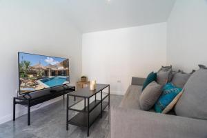 uma sala de estar com um sofá e uma televisão de ecrã plano em Manao Pool Villa 12 - 5 Mins Walk To The Beach em Ko Lanta
