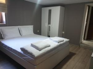 een slaapkamer met een bed met witte lakens en kussens bij Ракшиева Къща in Glavatartsi