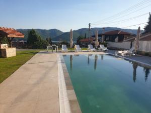 een groot zwembad met stoelen en een huis bij Ракшиева Къща in Glavatartsi