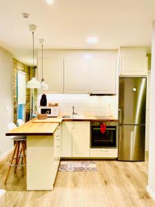 a kitchen with white cabinets and a stainless steel refrigerator at Loft centro Pontevedra in Pontevedra