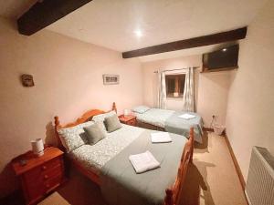 a bedroom with two beds and a dresser at RURAL stone barn with Log Burner, tranquil setting in Usk