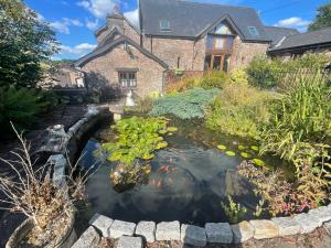 a koi pond in front of a house at RURAL stone barn with Log Burner, tranquil setting in Usk