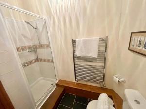 a white bathroom with a shower and a toilet at RURAL stone barn with Log Burner, tranquil setting in Usk