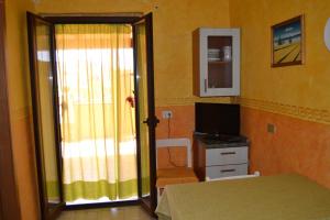 a bedroom with a bed and a television and a window at Casa Vacanze da Giuseppina in Lampedusa