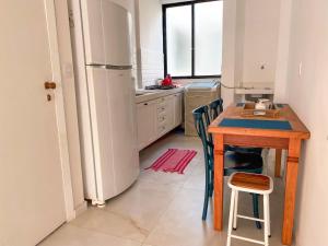 a kitchen with a wooden table and a refrigerator at Delicinha, a 5 minutos à pé da Praia do Forte in Cabo Frio