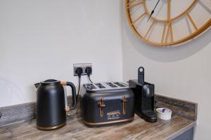um balcão com comodidades para preparar café, uma torradeira e um relógio em Seashell House with SEA VIEWS and FREE GYM POOL PASS em Amble