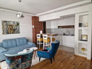 a living room with a blue couch and a kitchen at Apartman Malakal in Lukavica