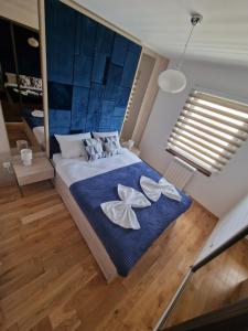 a bedroom with a large bed with blue and white sheets at Apartman Malakal in Lukavica