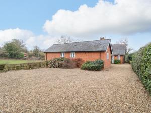 ein rotes Backsteinhaus mit einer Kiesauffahrt in der Unterkunft Valley Farm Cottage in Woodbridge
