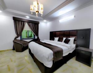 a bedroom with a large bed and a chandelier at Batw باتوا لشقق المخدومة in Al Baha