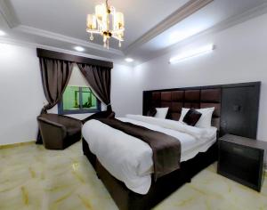 een slaapkamer met een groot bed en een kroonluchter bij Batw باتوا لشقق المخدومة in Al Baha