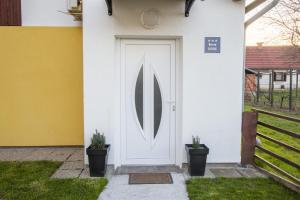 a white front door of a house with two potted plants at Soba - Room - Zimmer M in Karlovac