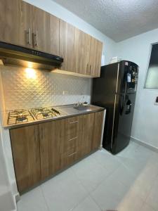 a kitchen with wooden cabinets and a black refrigerator at Apartamento en Cartagena in Cartagena de Indias