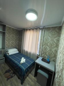 a small bedroom with a bed and a table at Fam_House in Bishkek