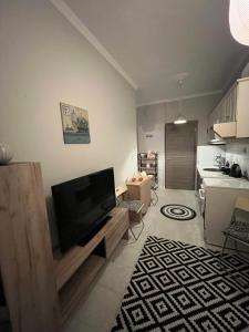 a living room with a flat screen tv and a kitchen at Casita Una in Ofrínion