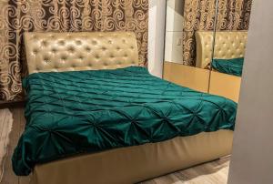 a bed with a green comforter and a mirror at Pensiunea Brezu in Sighetu Marmaţiei