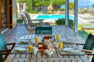 a wooden table with food and orange juice on it at Terra Casa Private Villa in Aegina Island in Vathí