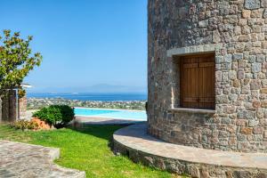a stone building with a wooden door next to a pool at Terra Casa Private Villa in Aegina Island in Vathí
