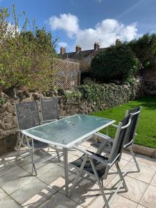 a glass table and two chairs on a patio at Cardiff Home in Cardiff