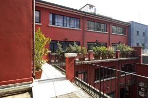 un edificio rosso con piante in vaso sui balconi di Oasi Village Hotel a Milano